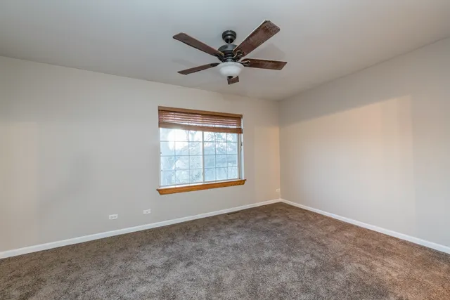 an empty room with ceiling fan and window