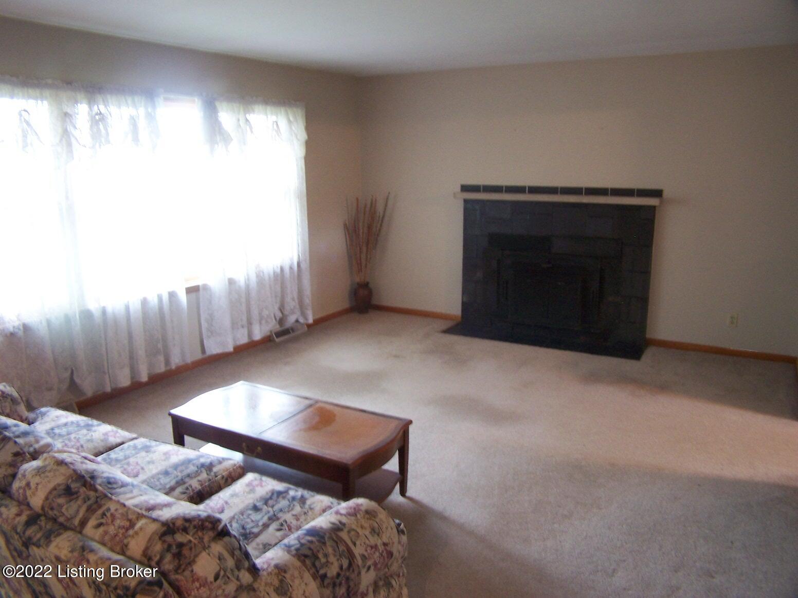 6976 Sulphur Road Sulphur, KY 40070 - Photo 18 of 31 Living Room with large picture window, buck stove and hardwood floors underneath carpeting.