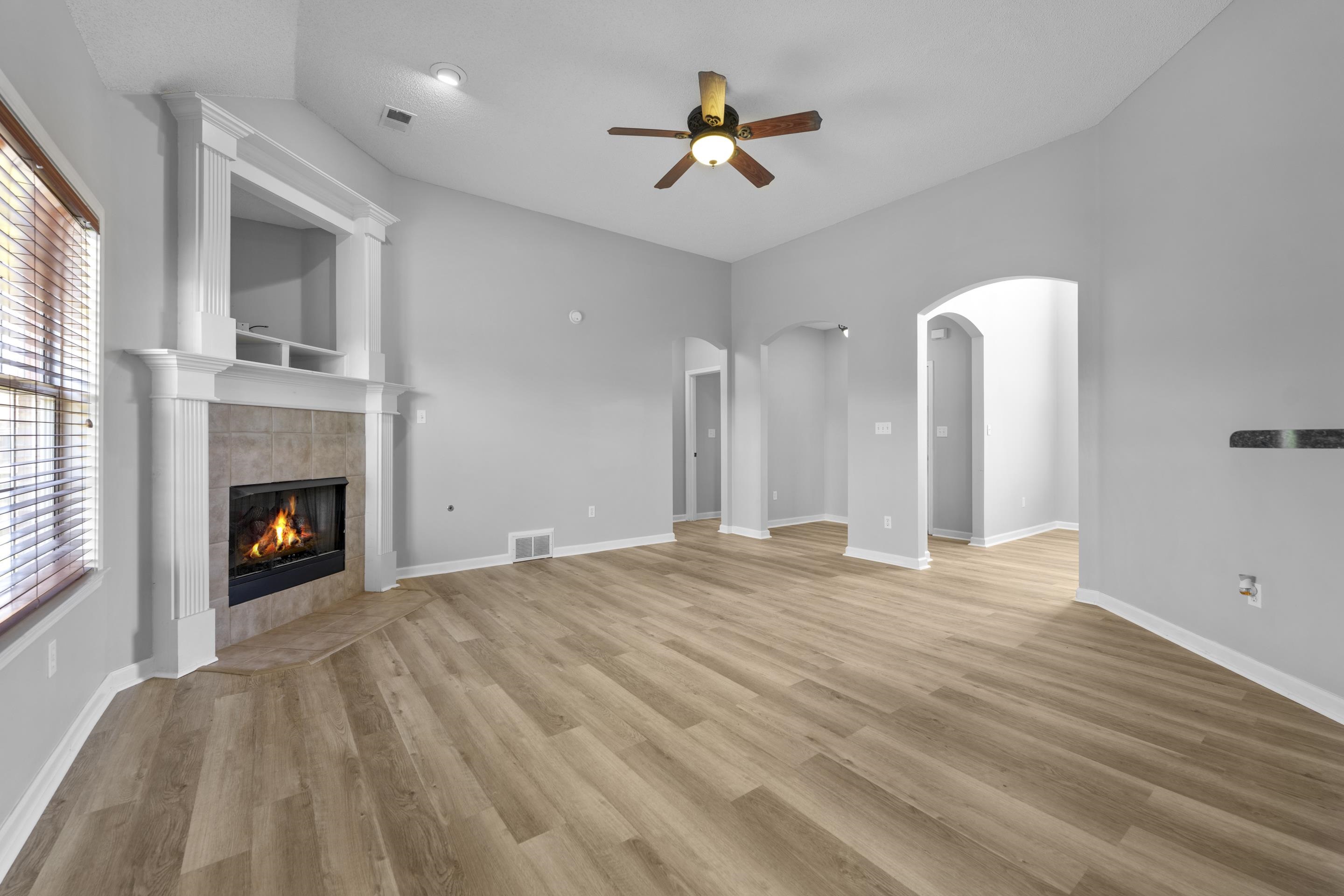 50 Abbey Road Oakland, TN 38060 - Photo 4 of 26 Open concept living area featuring wood-finish flooring, a corner fireplace with a tiled surround, and vaulted ceilings