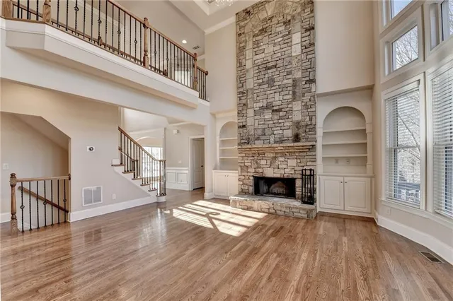 a large kitchen with granite countertop a stove a sink a center island and wooden floor