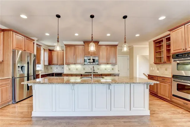 a kitchen with stainless steel appliances granite countertop a stove a sink and white cabinets with wooden floors