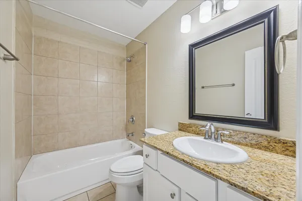 a bathroom with a granite countertop sink toilet mirror and bathtub