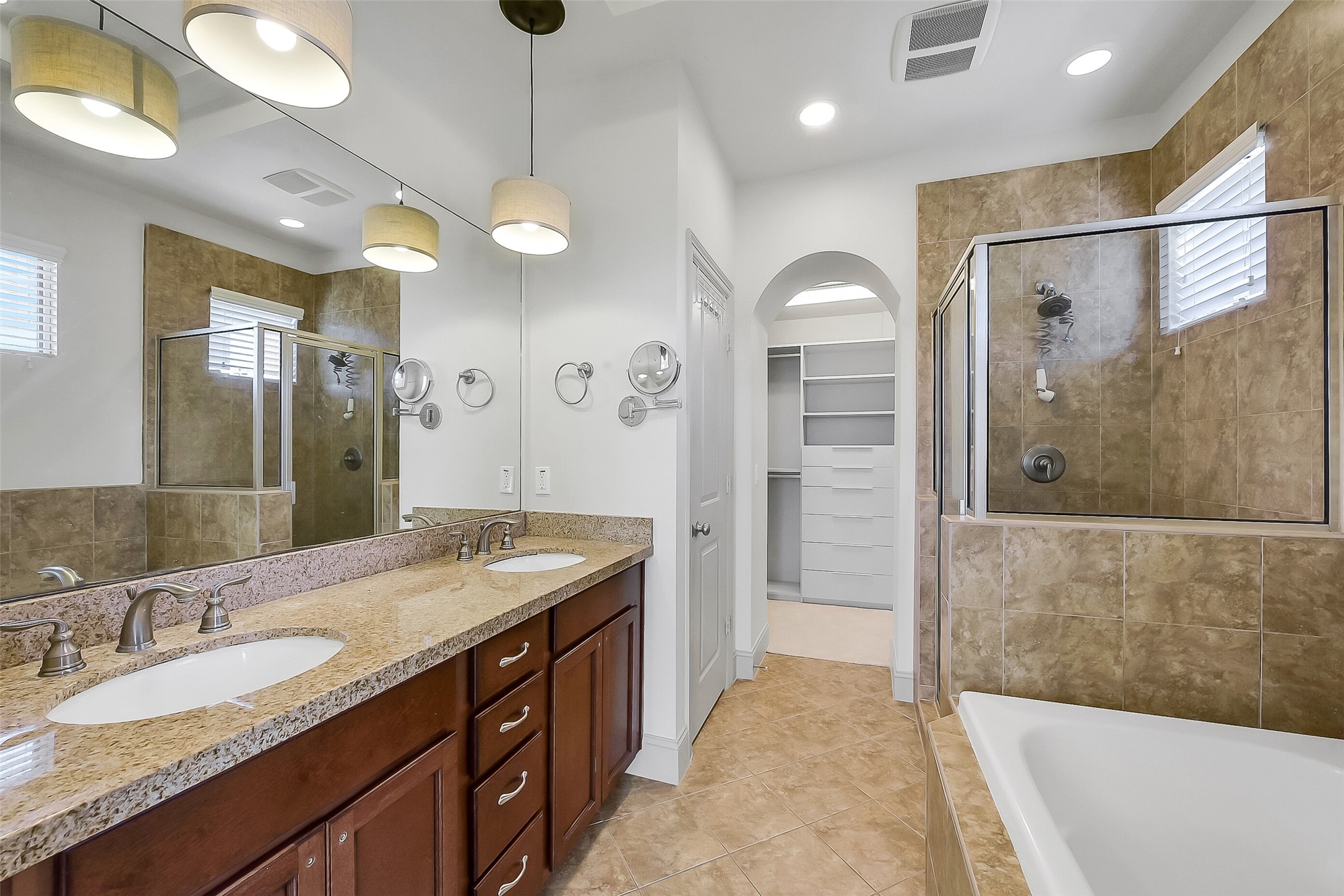 1929 Summer Street Houston, TX 77007 - Photo 16 of 27 Beautiful primary bathroom features a dual-sink vanity with granite countertop and storage, decorative pendant vanity lights, walk-in shower, and a separate jetted tub with tile surround. Additional highlights include: 10’ tray ceiling, tile flooring, and two privacy windows.