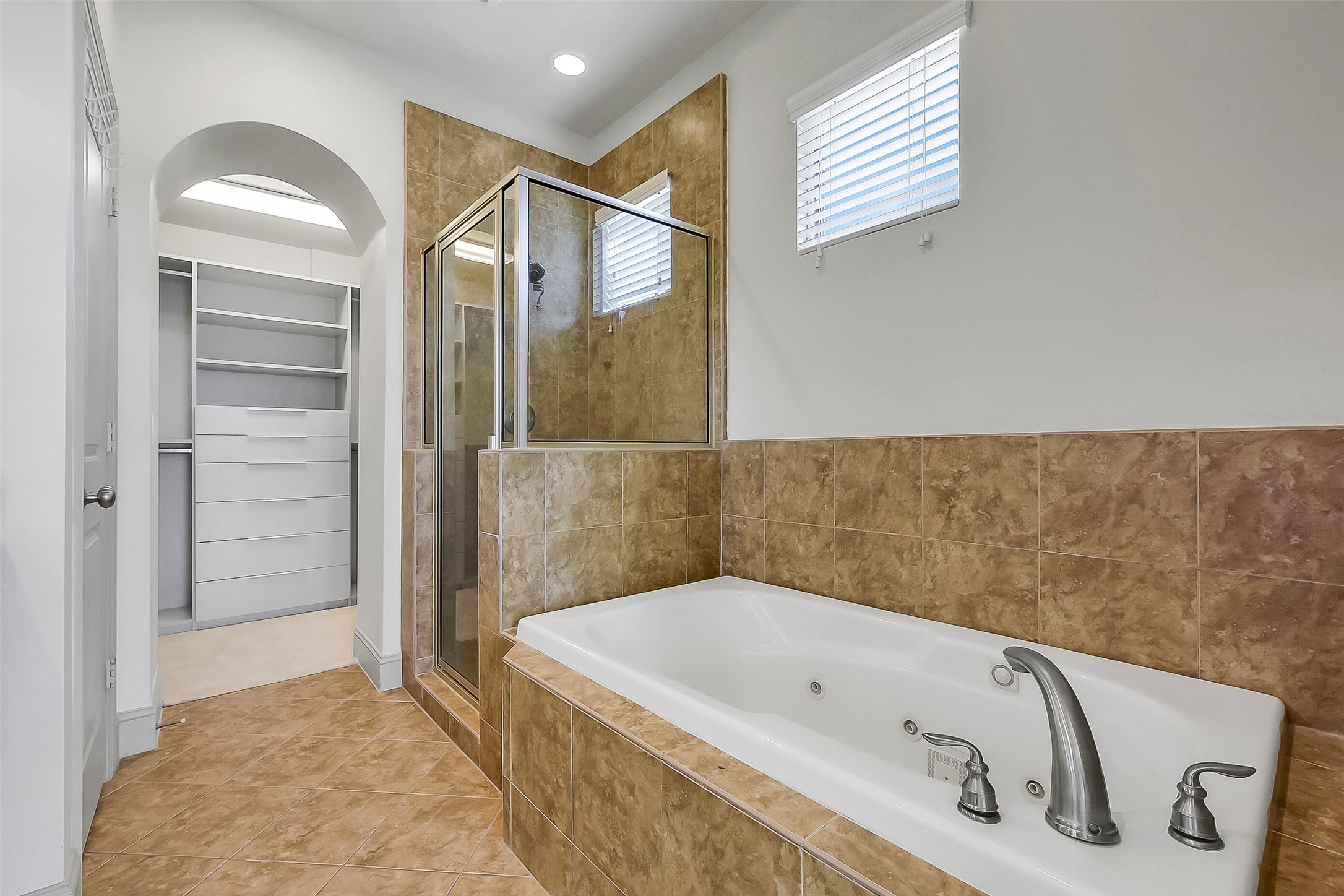 1929 Summer Street Houston, TX 77007 - Photo 17 of 27 Another angle of the primary bath showing the walk-in shower with glass door, separate jetted tub, and tile surround, private water closet, and walk-in closet with added built-in storage.