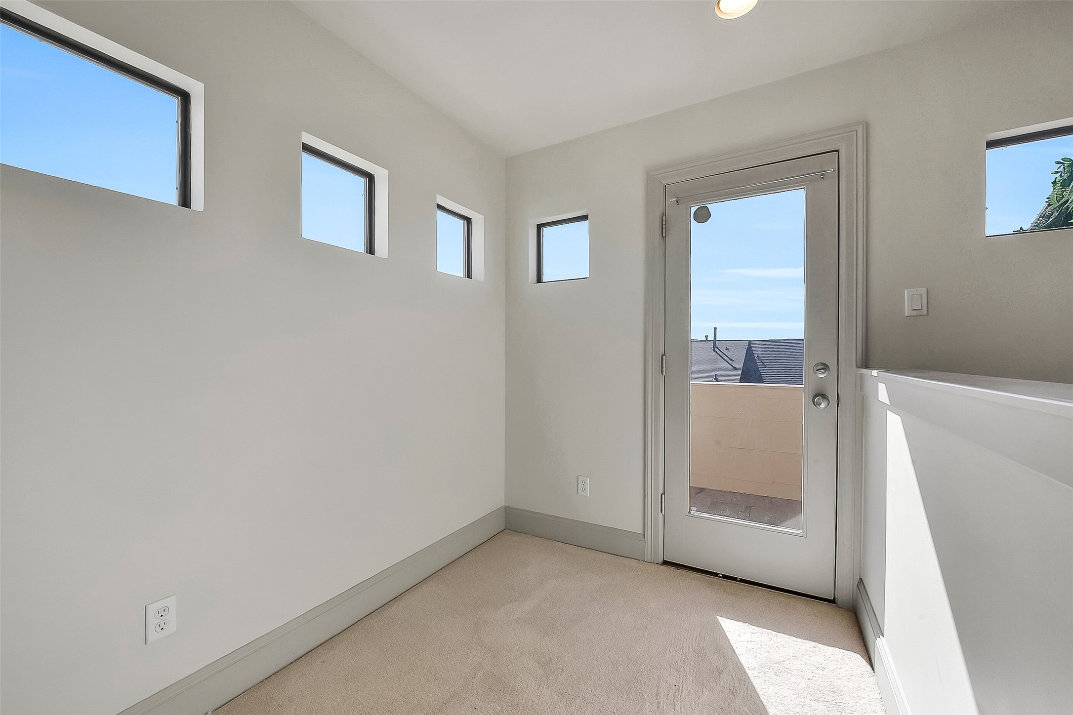 1929 Summer Street Houston, TX 77007 - Photo 22 of 27 At the top of the stairs leading to the rooftop terrace, a convenient fourth-floor landing offers room for a desk or bar area. Features include: windows for natural light, new carpet (2025), attic access, and an exterior door leading out to the terrace.