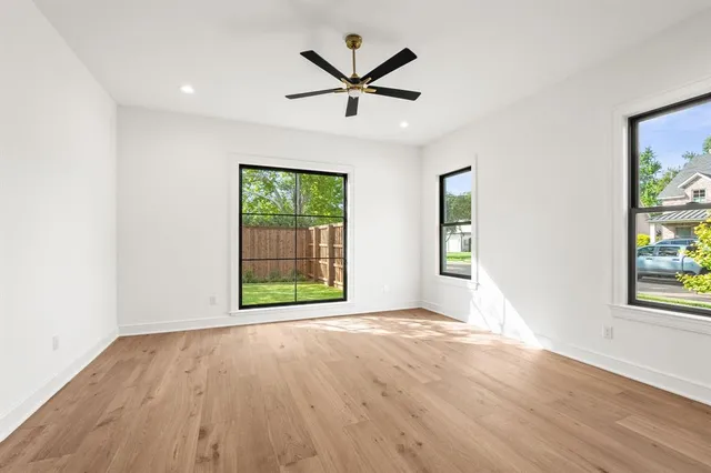 an empty room with windows and ceiling fan