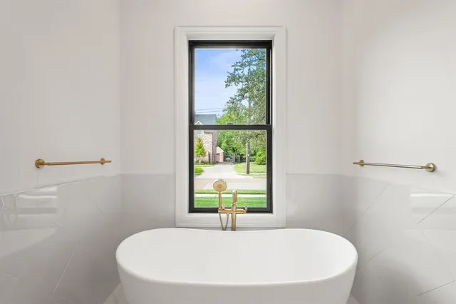 a white bath tub sitting in a bathroom next to a window
