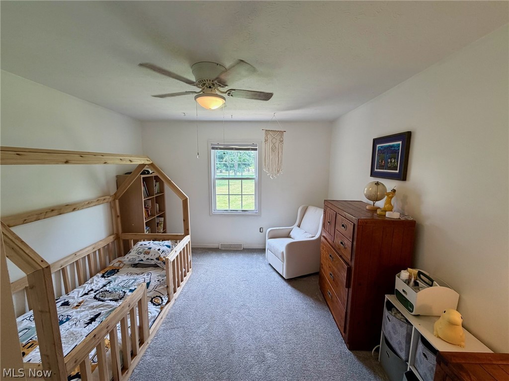 37373 Butternut Ridge Road North Ridgeville, OH 44039 - Photo 19 of 22 Bright nursery with natural light from a large window, ceiling fan with integrated lighting, hardwood crib with storage shelving, wood-finish dresser with ample drawer storage, plush seating chair, and carpeted flooring throughout