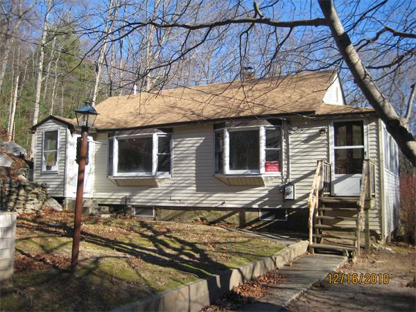 105 Whitins Road Sutton, MA 01590 - Photo 1 of 1 a yellow house with table and chairs under an umbrella