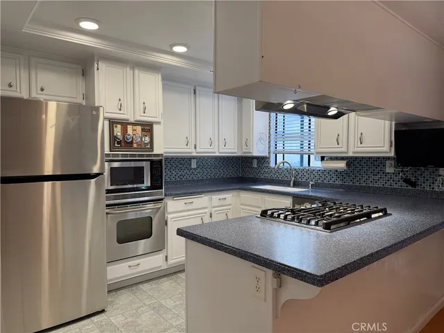 a kitchen with stainless steel appliances granite countertop a stove refrigerator sink and microwave