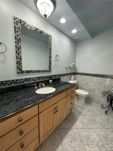a bathroom with a granite countertop sink a toilet and a mirror