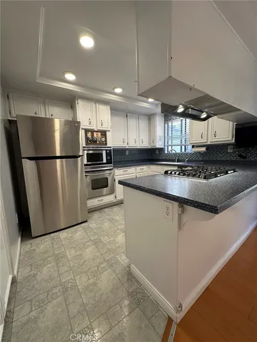 a kitchen with stainless steel appliances granite countertop a refrigerator a sink a stove a microwave and island