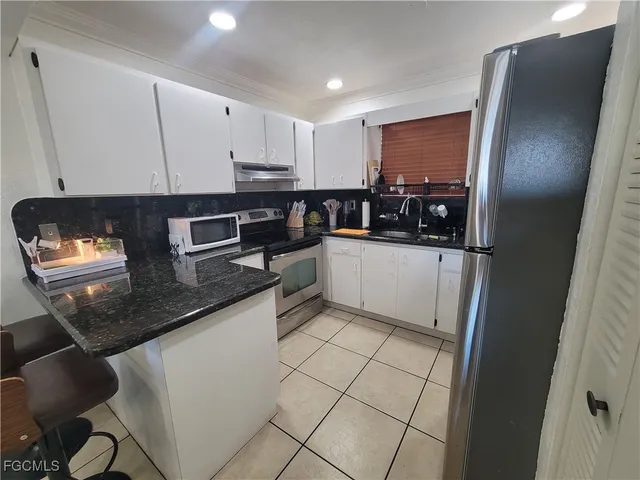 a kitchen with stainless steel appliances granite countertop a refrigerator a stove and a sink