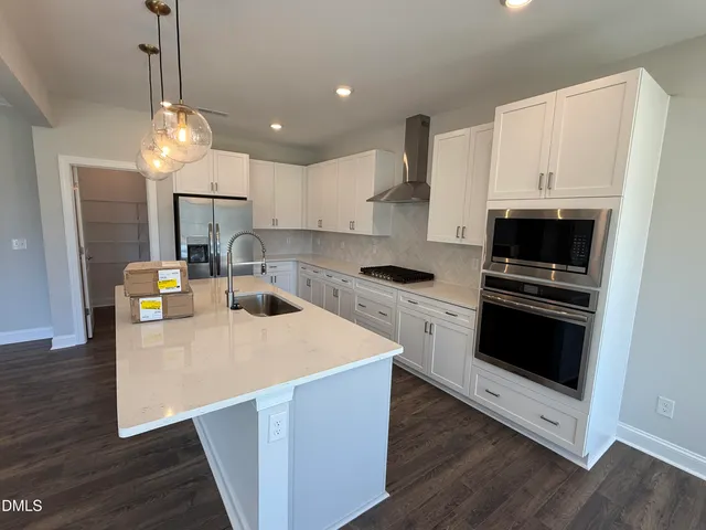 a kitchen with kitchen island a stove a microwave a sink a refrigerator and white cabinets