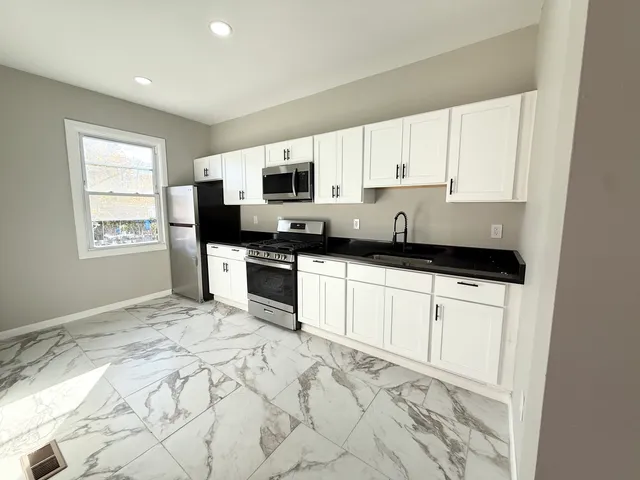 a kitchen with granite countertop a stove a sink and a microwave
