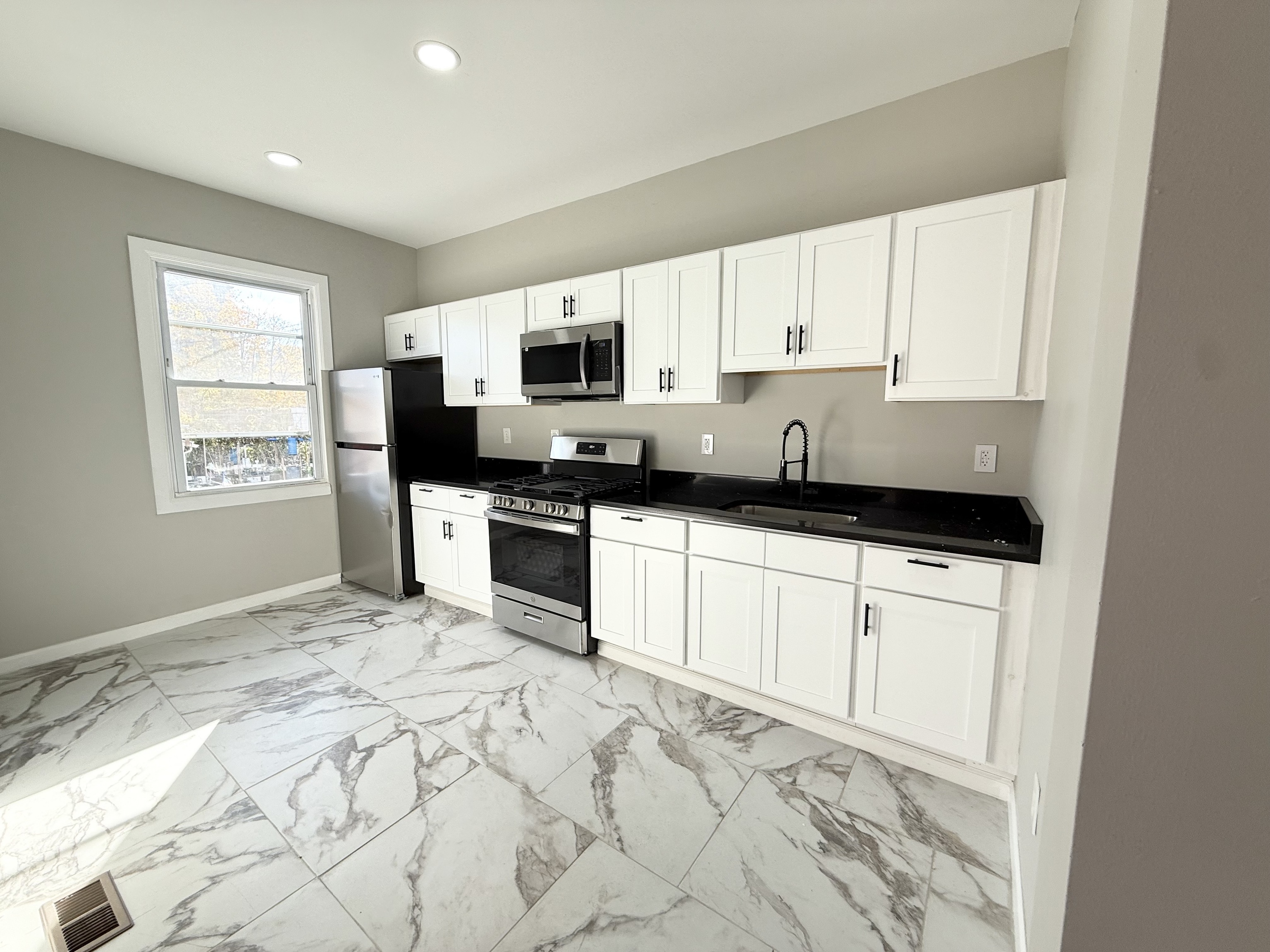 a kitchen with granite countertop a stove a sink and a microwave