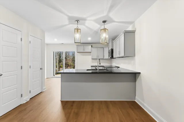 a kitchen with stainless steel appliances a sink and wooden floor