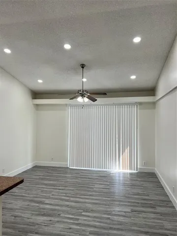 an empty room with wooden floor chandelier and windows
