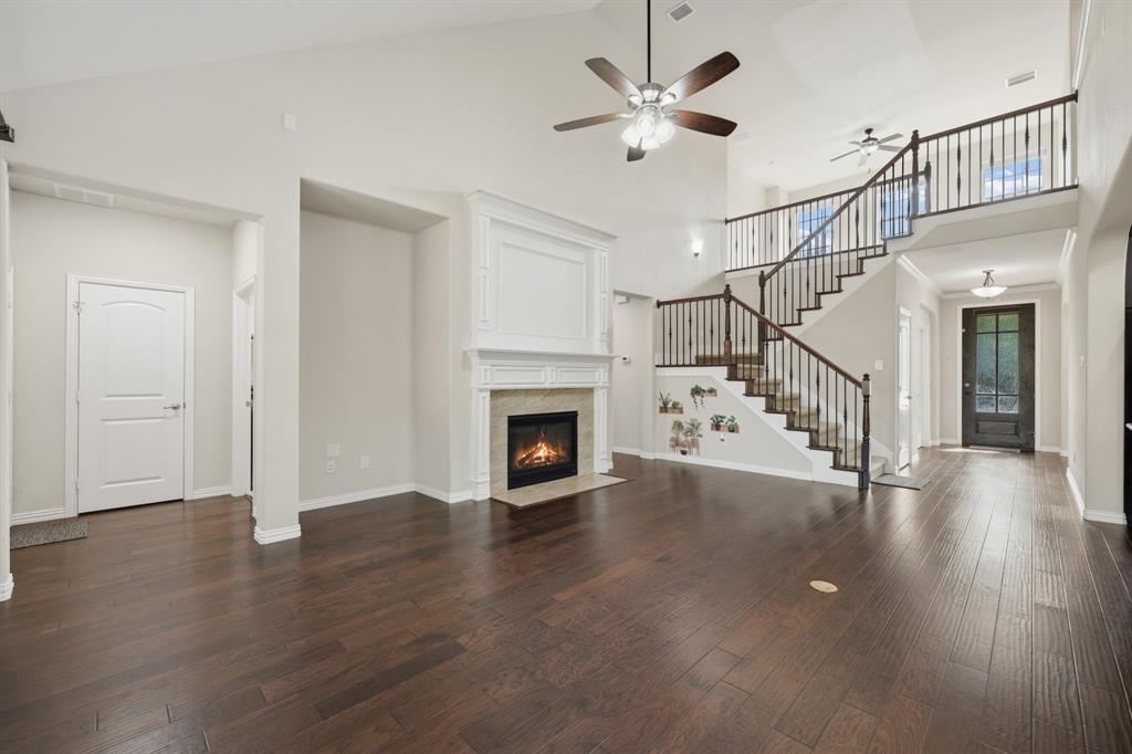 12809 Spring Hill Drive Frisco, TX 75035 - Photo 17 of 37 a view of a livingroom with wooden floor a fireplace a ceiling fan and windows