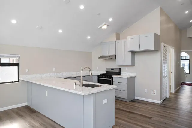 a kitchen with a sink white cabinets and stainless steel appliances