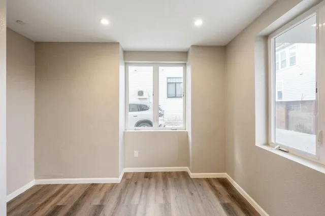 an empty room with wooden floor and windows