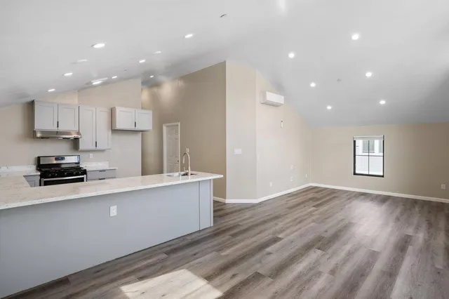 a large kitchen with stainless steel appliances a large counter top a stove a sink and a refrigerator