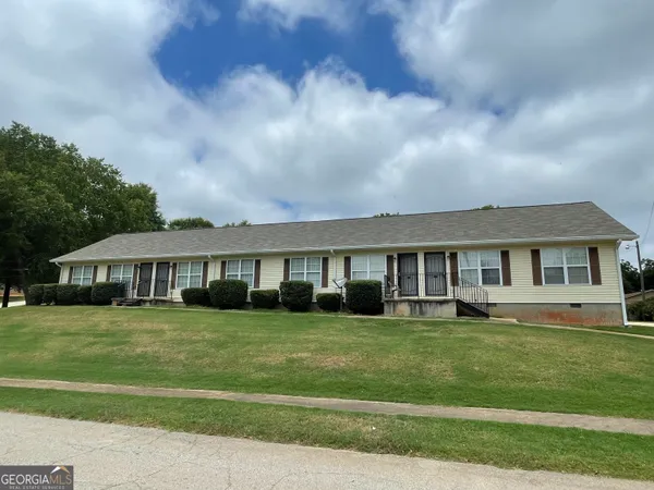 a view of a house next to a big yard and large trees