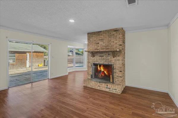 a view of an empty room with wooden floor fireplace and a window