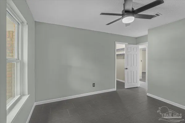 an empty room with a window and ceiling fan
