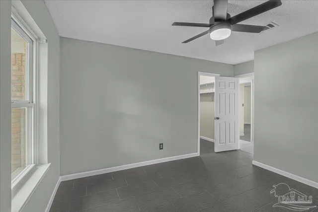 an empty room with a window and ceiling fan