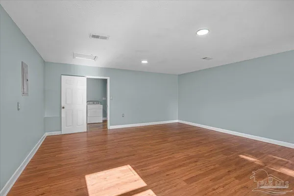 an empty room with wooden floor and windows