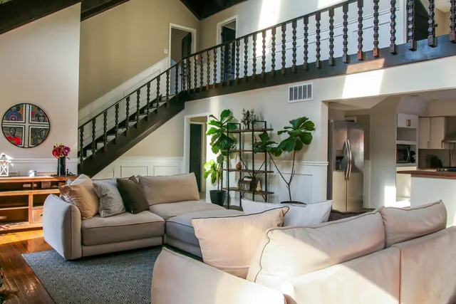 a living room with furniture stairs and a potted plant