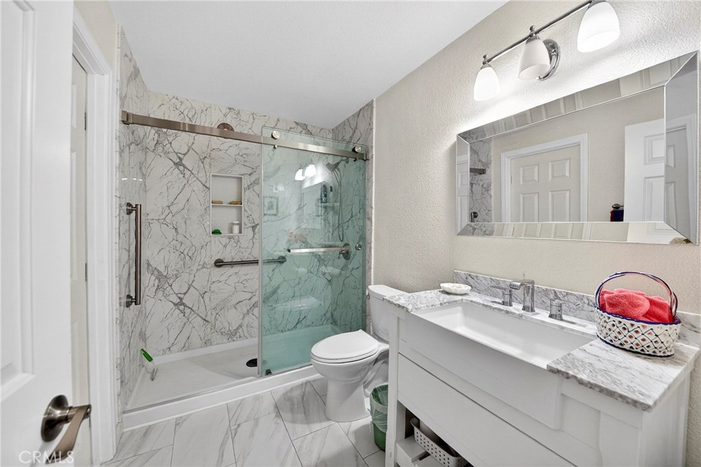 6109 Vineyard Avenue Rancho Cucamonga, CA 91701 - Photo 12 of 22 a bathroom with a granite countertop sink a toilet and shower