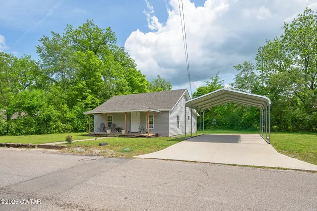 a front view of a house with a yard and trees