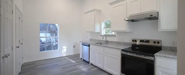 a kitchen with a stove and a white wooden cabinets