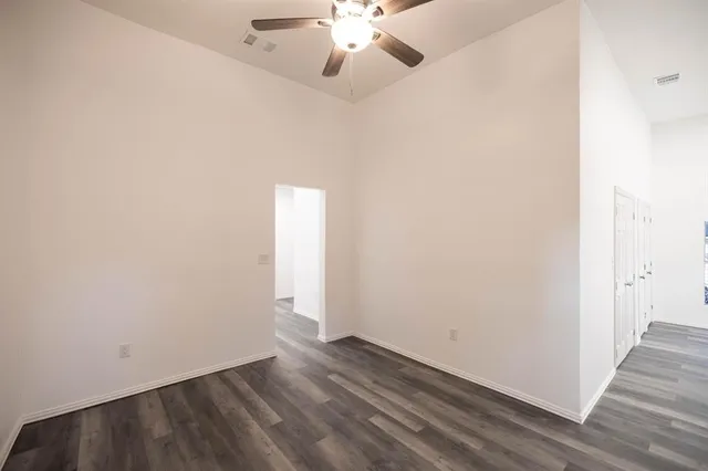 an empty room with wooden floor fan and window