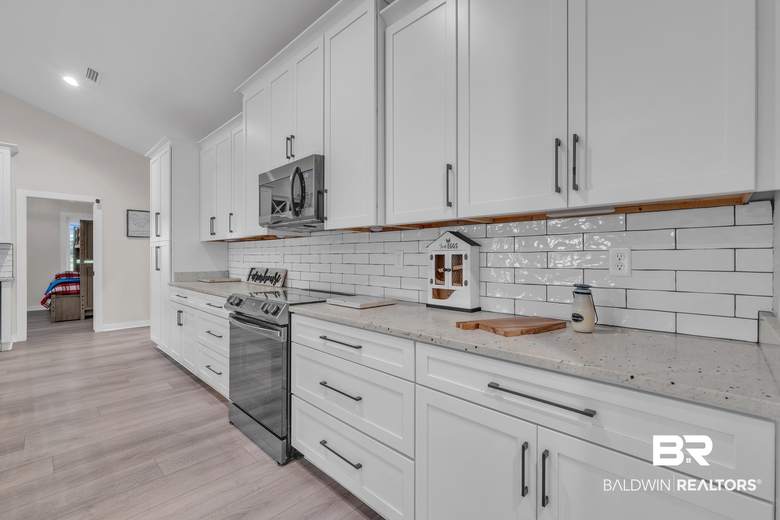 22592 Pastoral Lane Foley, AL 36535 - Photo 11 of 45 Kitchen with appliances with stainless steel finishes, tasteful backsplash, white cabinets, light wood-style flooring, and lofted ceiling