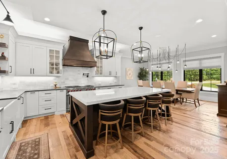 a kitchen with stainless steel appliances granite countertop a stove a sink dishwasher a dining table and chairs with wooden floor