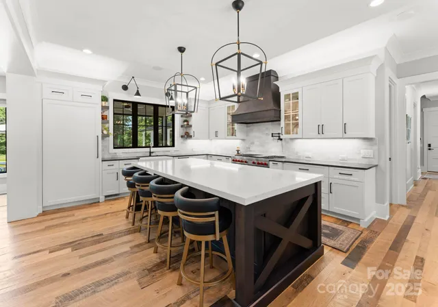 a kitchen with stainless steel appliances kitchen island granite countertop a table chairs in it and white cabinets