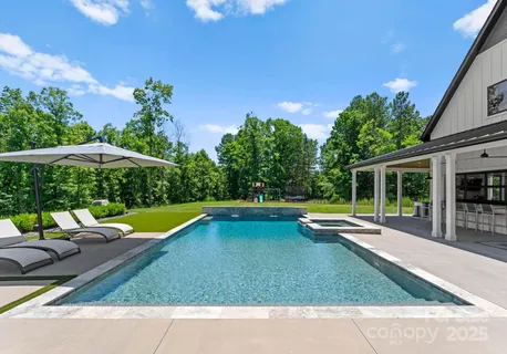 a view of swimming pool with lawn chairs and plants