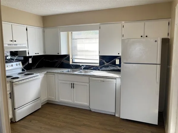 a kitchen with granite countertop white cabinets and sink