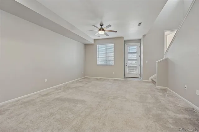 an empty room with chandelier fan and windows
