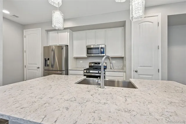 a kitchen with kitchen island a refrigerator and a stove top oven