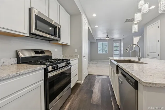 a kitchen with stainless steel appliances granite countertop a stove a sink and a microwave