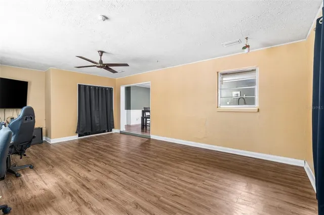 a view of empty room with wooden floor and fan