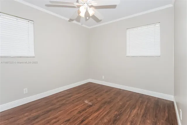 an empty room with wooden floor and fan