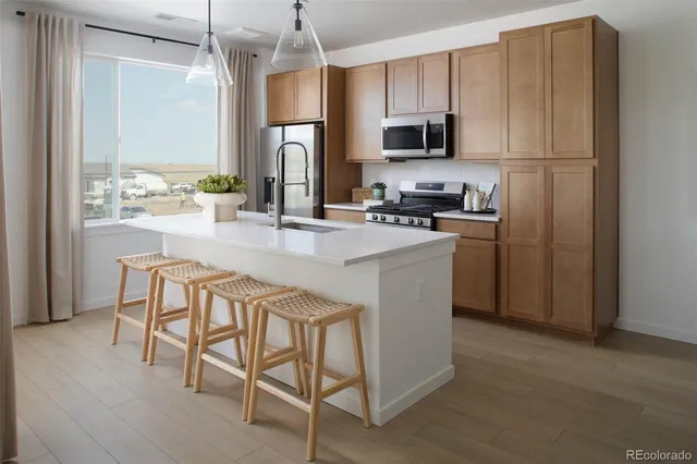 a kitchen with stainless steel appliances granite countertop a stove top oven a refrigerator a sink and a dining table with wooden floor