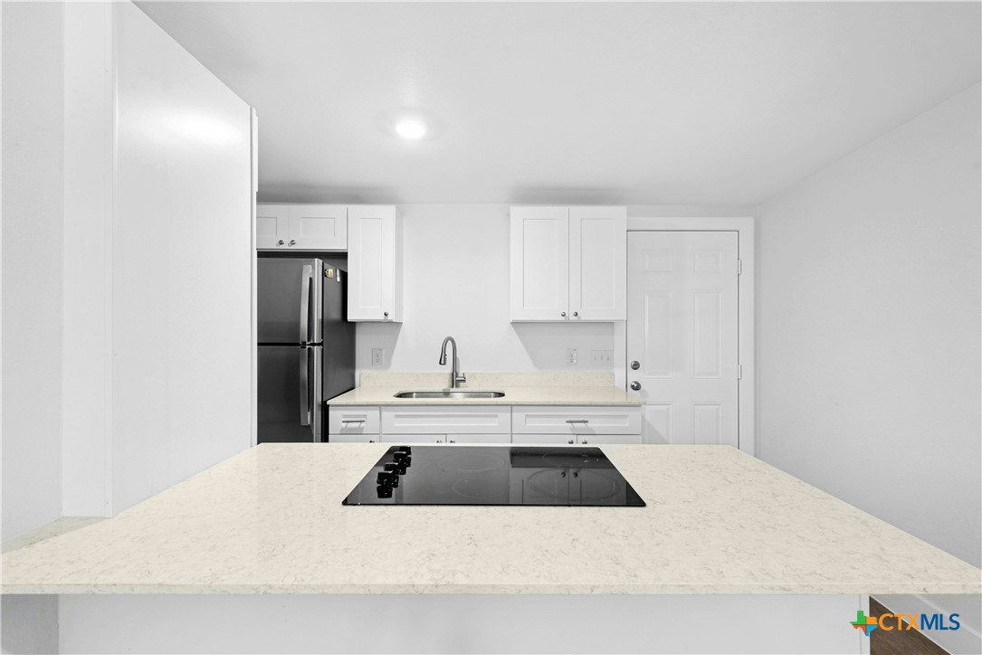 1007 Hackberry Street San Marcos, TX 78666 - Photo 17 of 36 a kitchen with a sink a refrigerator and white cabinets