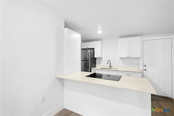 a kitchen with kitchen island a stove and white cabinets