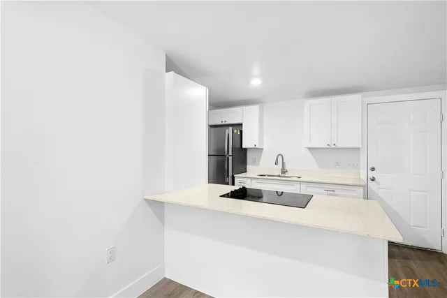 a kitchen with kitchen island a stove and white cabinets